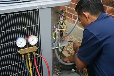 Extreme Comfort HVAC technician checking AC refrigerant levels during a cooling system inspection.