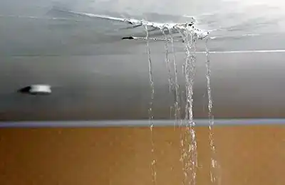 Severe ceiling damage with water leaking from a hole, caused by a clogged HVAC drain line.