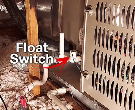 Close-up of a white float switch (condensate overflow switch) installed on an HVAC drain line.