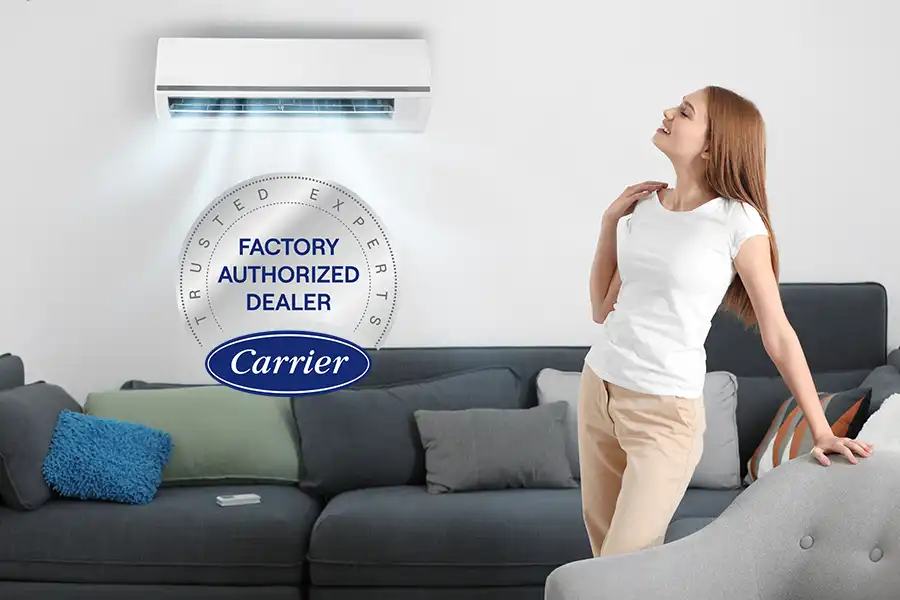 Woman enjoying cool air from a wall mounted ductless mini split with a Carrier Factory Authorized Dealer badge